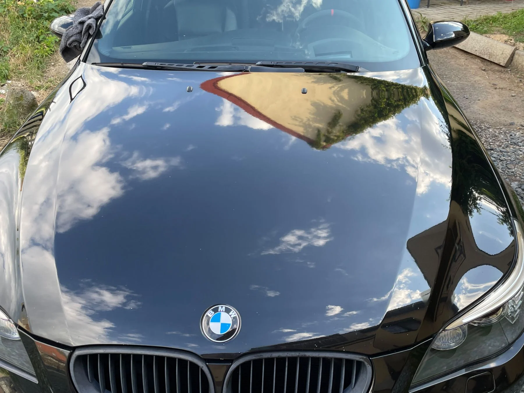 Vyleštěná kapota černého BMW s odrazem oblohy po detailingu